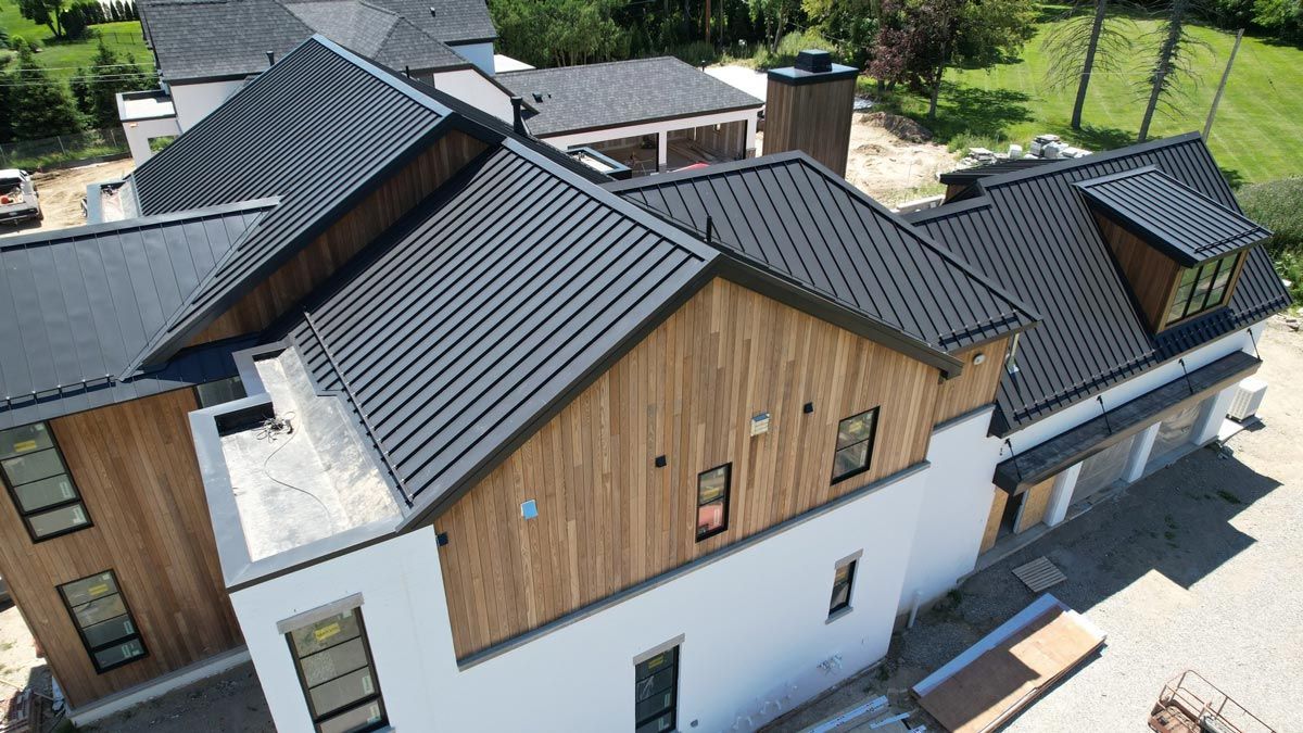 Drone shot capturing a different angle of the home in Birmingham, Michigan, showcasing the matte black standing seam metal roof. This perspective emphasizes the roof's sharp, clean lines and how it complements the overall architecture of the property.