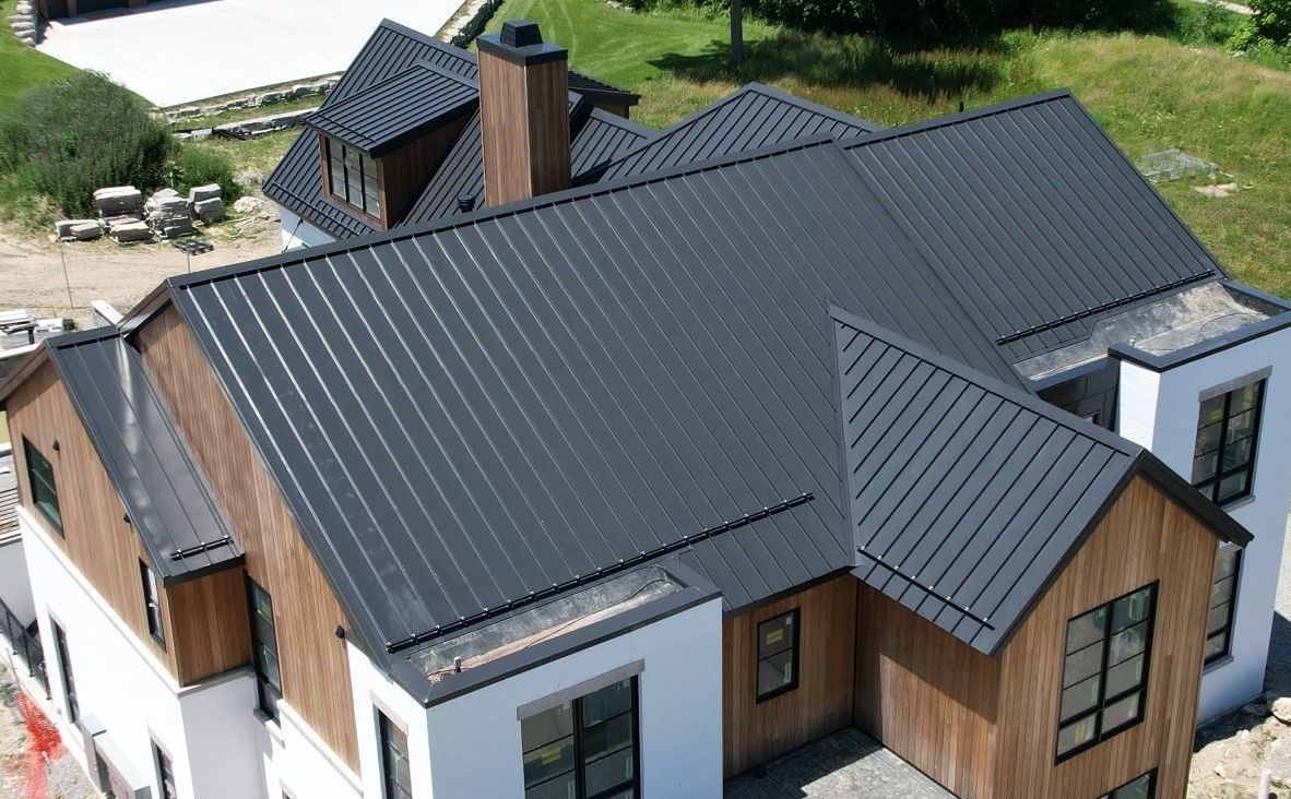 Aerial view of a modern home in Birmingham, Michigan, showcasing a matte black standing seam metal roof. The shot emphasizes the sleek lines and seamless installation, highlighting the durability and contemporary design of Michigan metal roofing.