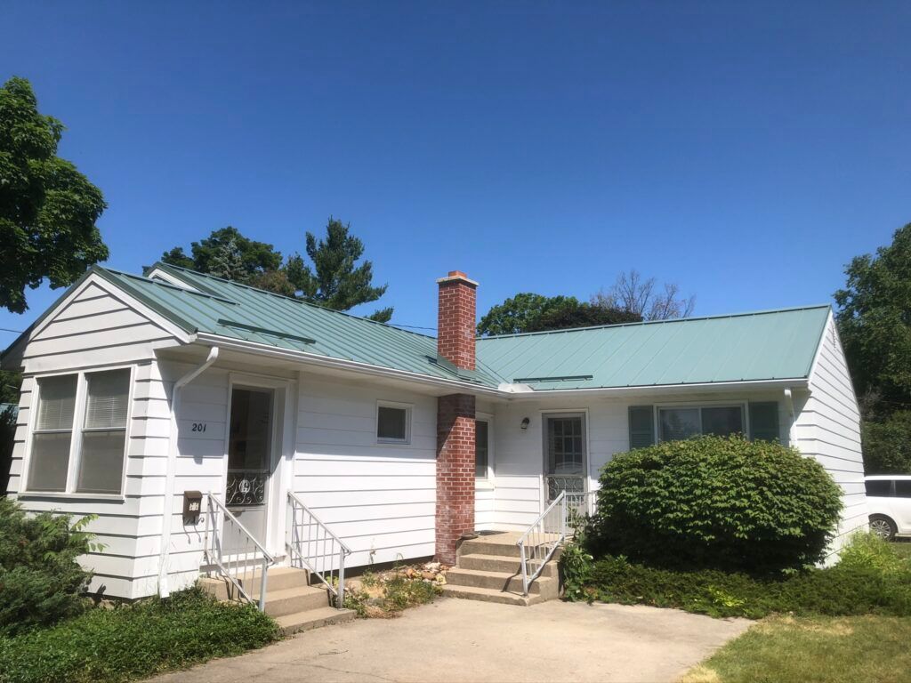 Charlevoix, Michigan roofing project featuring Hemlock Green standing seam metal panels, installed by skilled Northern Michigan roofers.
