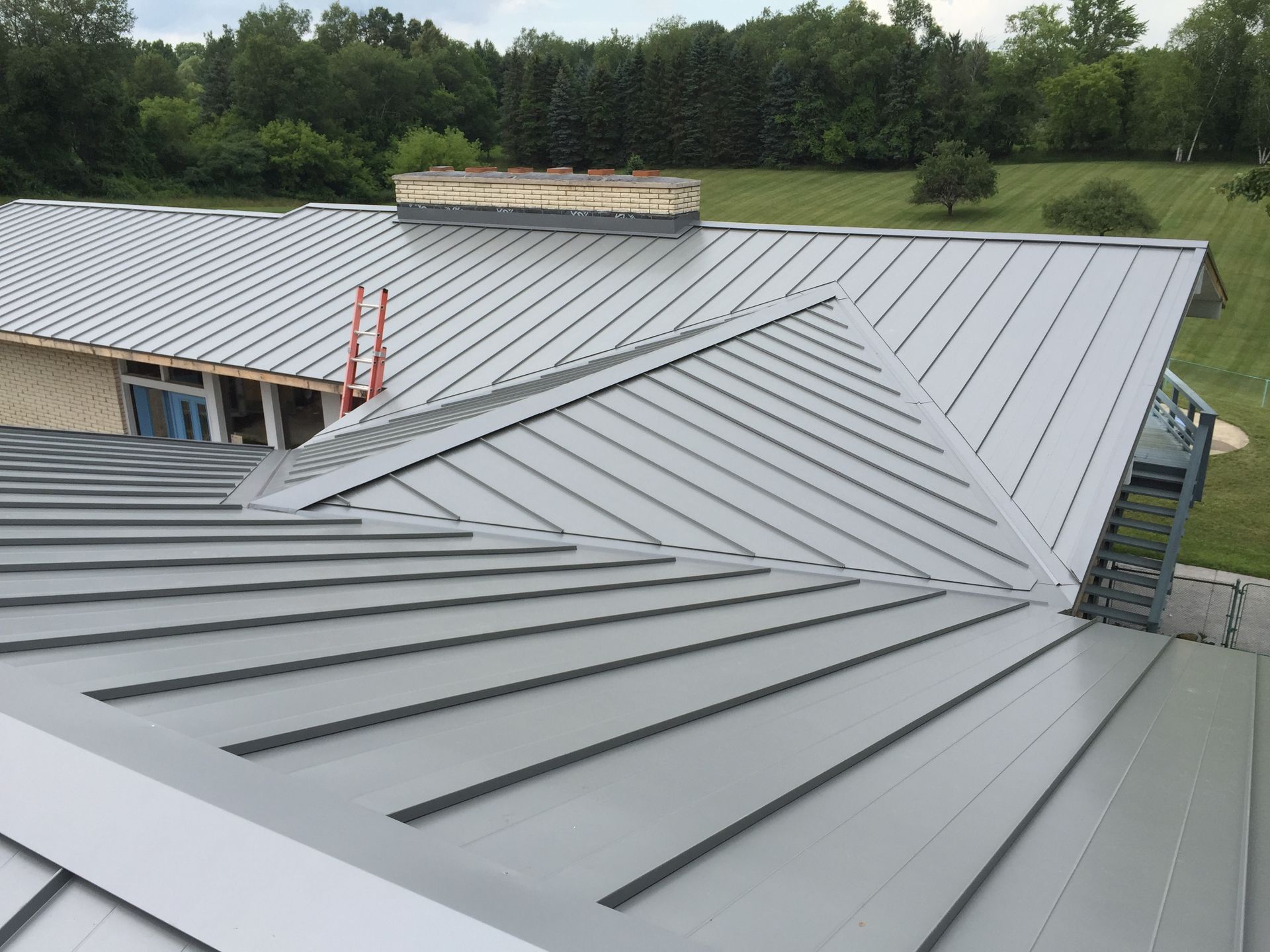 Roofing contractor in Gaylord, MI, showcasing a sleek standing seam metal roof with seamless installation and modern design from an aerial view.