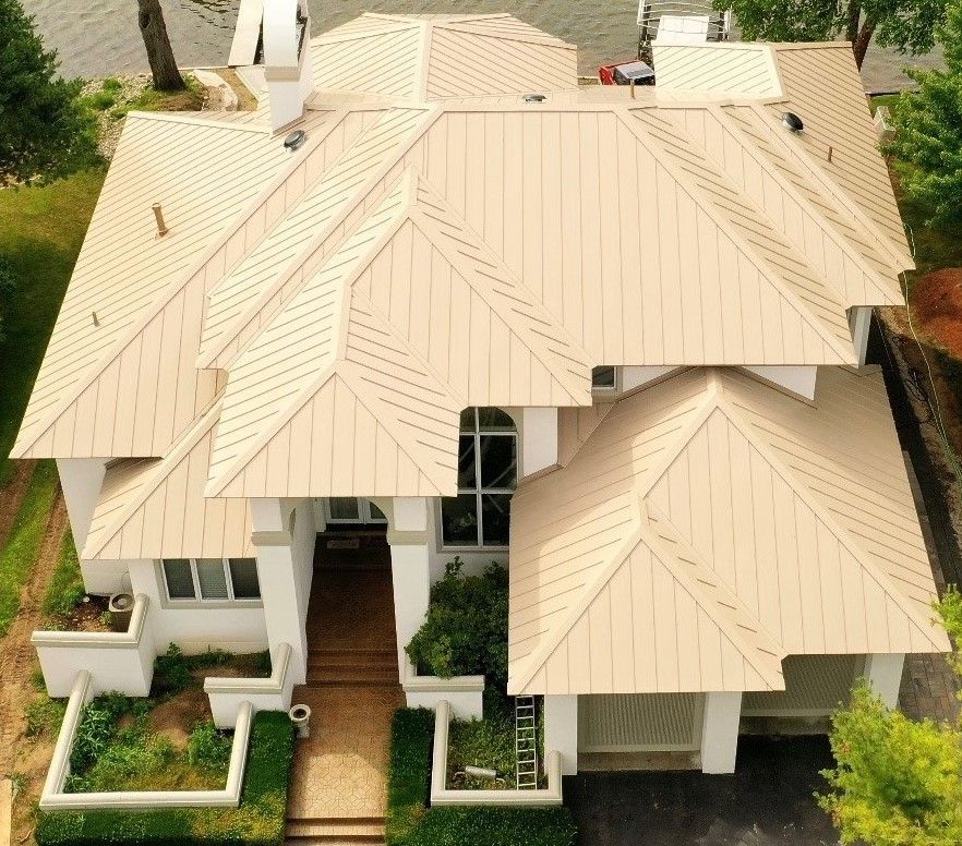Completed metal roof project 'Hipzilla' featuring 24ga Sierra Tan panels with custom trim, installed on a large residential home.