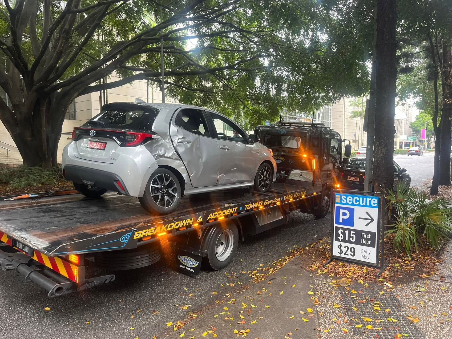 Burned silver car on a tow truck under trees beside a parking sign — A B & Forge Towing In Caboolture, QLD