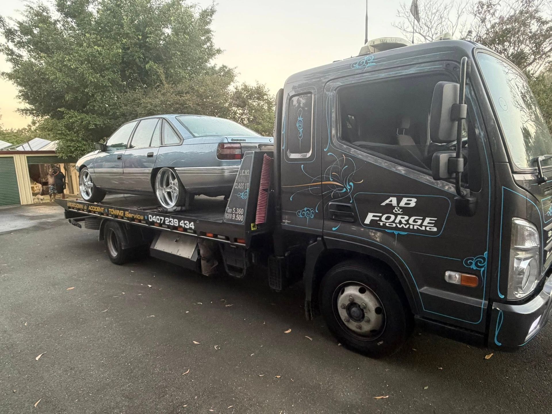 Tow Truck Carrying a Black Sedan on a Flatbed — A B & Forge Towing In Caboolture, QLD