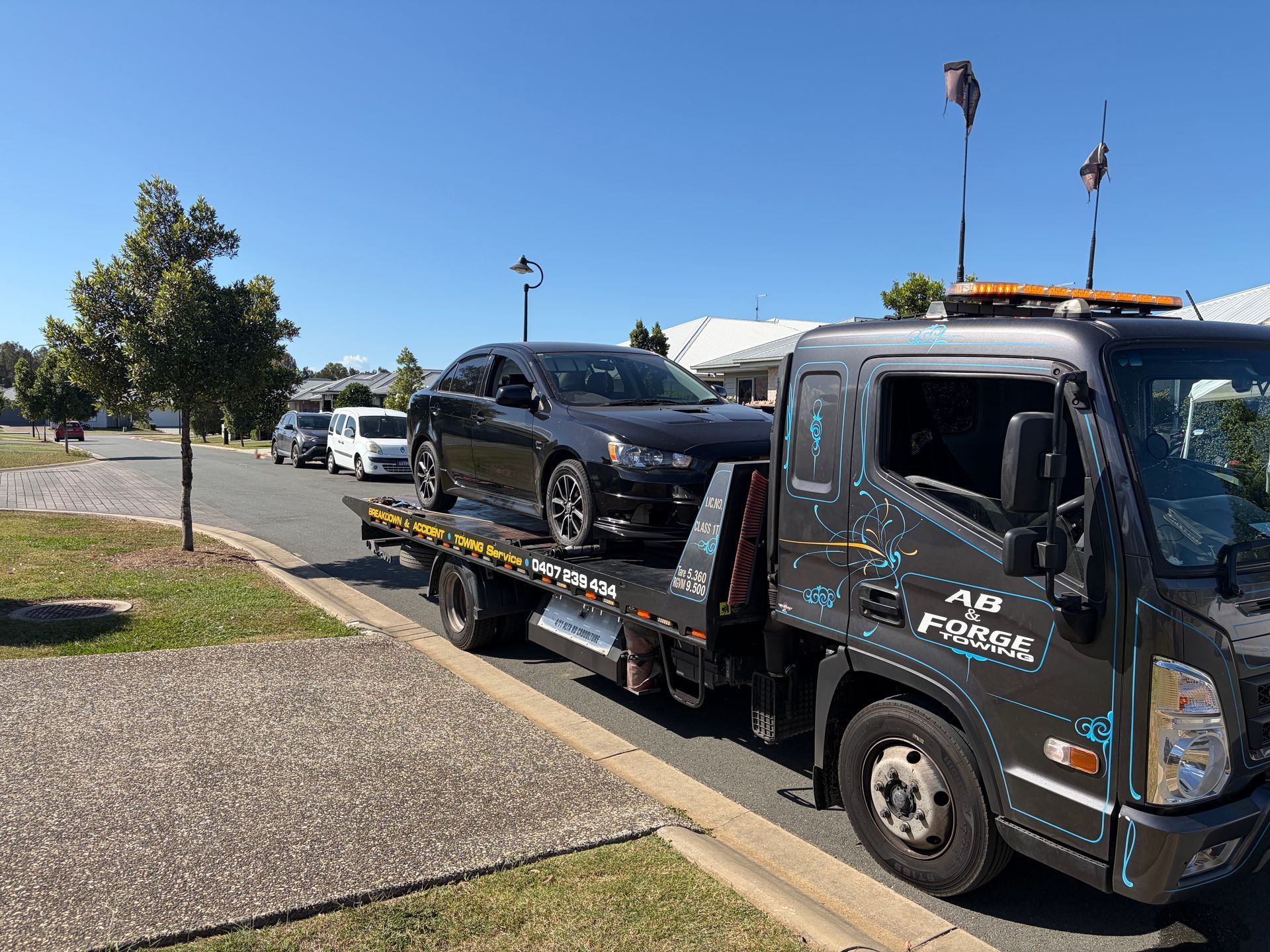 Tow Truck Hauling a Black Car on a Flatbed — A B & Forge Towing In Caboolture, QLD