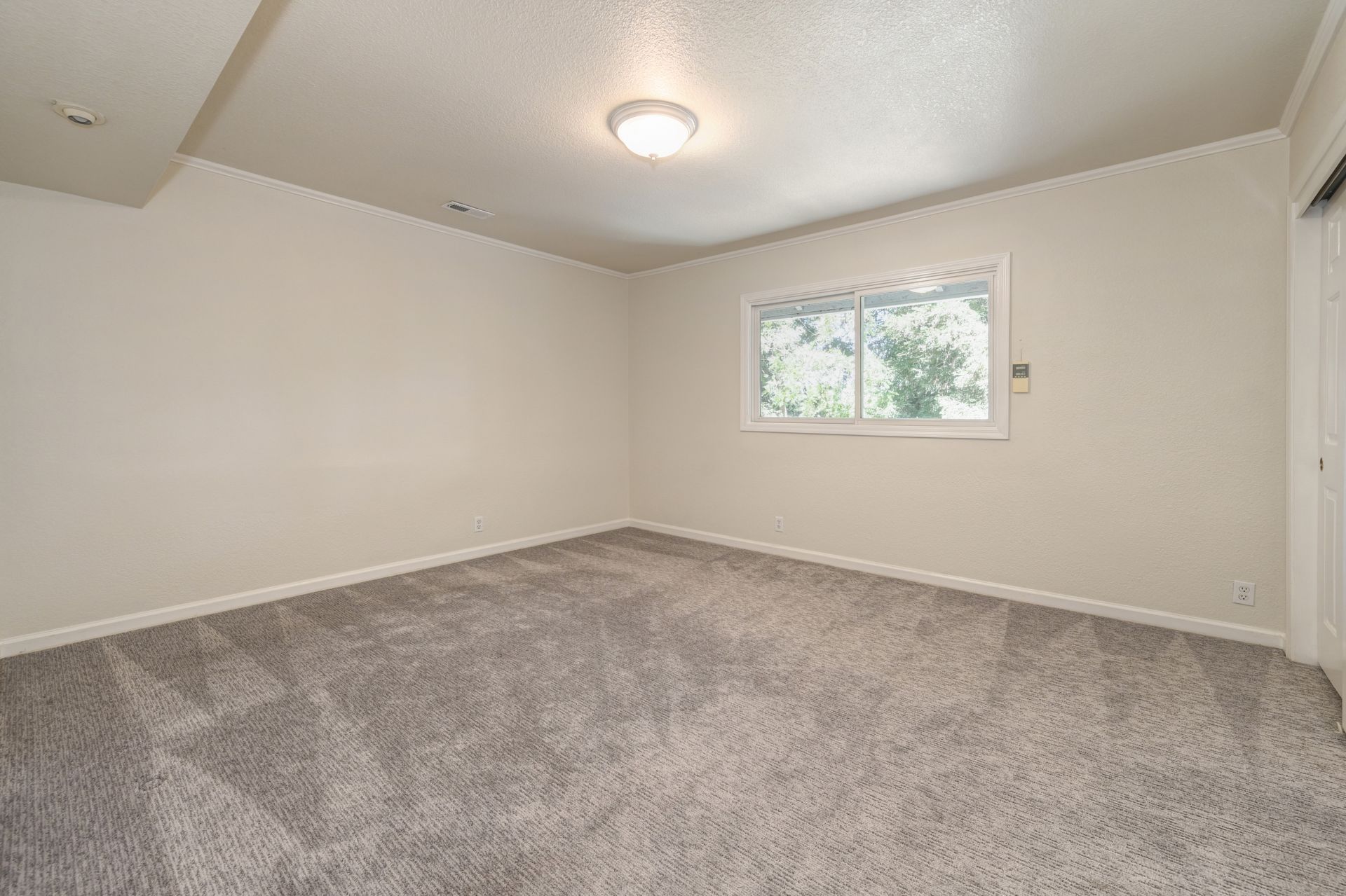An empty room with a carpeted floor and a window. Locate Homes for Sale in East Sac with Rich Cazneaux Real Estate Group