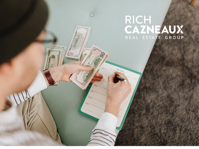 Person counting cash and writing on a notepad. Bills are fanned out on a table.
