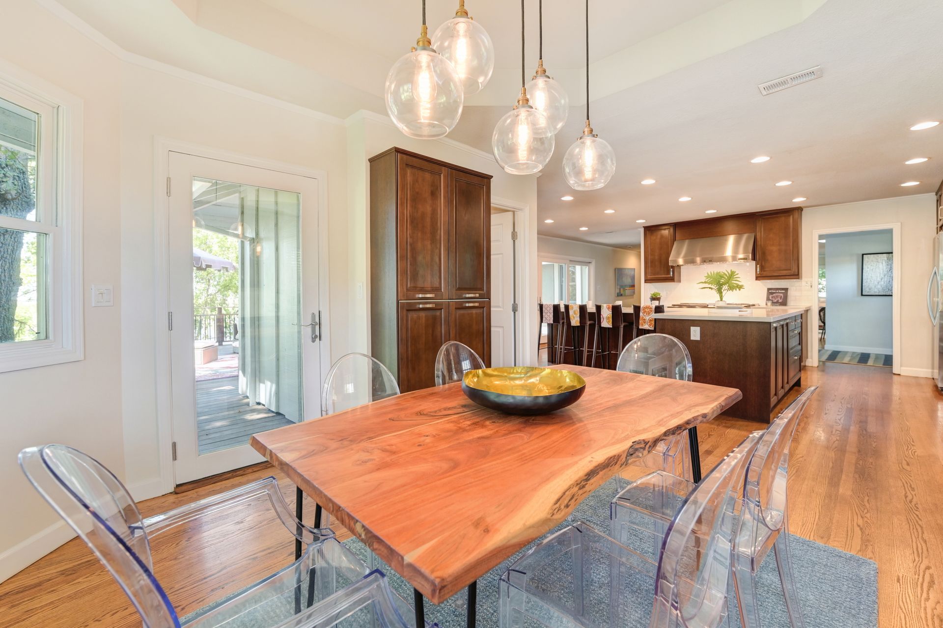 Modern dining room with clear chairs, wood accents, and a sleek kitchen view. Explore homes for sale in East Sacramento, CA.