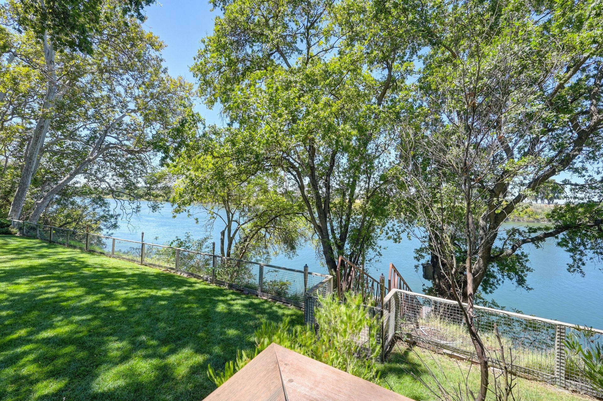 Fenced riverside yard with shady trees and water views. Discover homes for sale in East Sacramento with Rich Cazneaux.