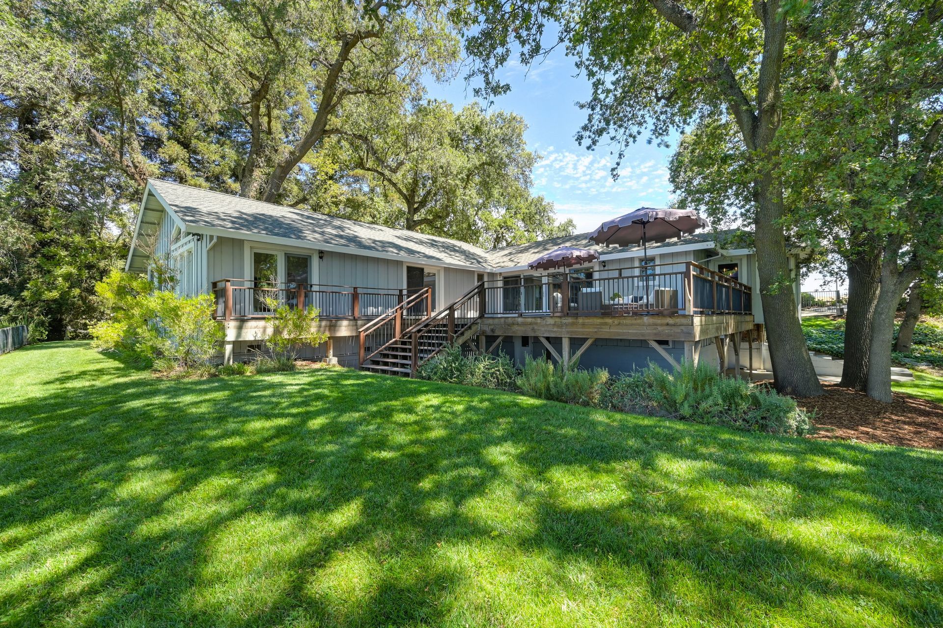 Sunny home with a wide deck and serene yard, surrounded by trees. Explore East Sacramento real estate with Rich Cazneaux.