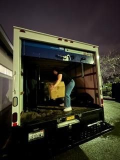 A man is loading a box into the back of a blue and white truck.