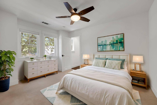 A bedroom with a large bed and a ceiling fan.