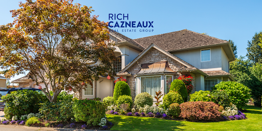 A large house with a well-maintained yard and landscaping. The sky is clear blue.