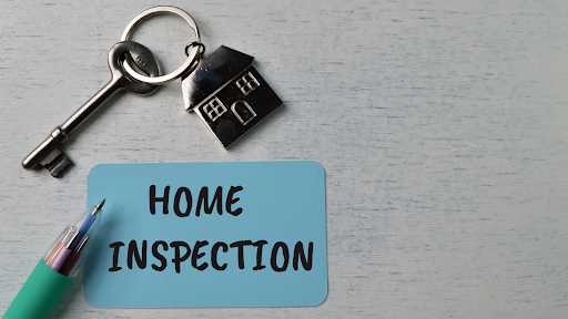 A key , a house keychain , a pen and a sticky note that says `` home inspection ''.