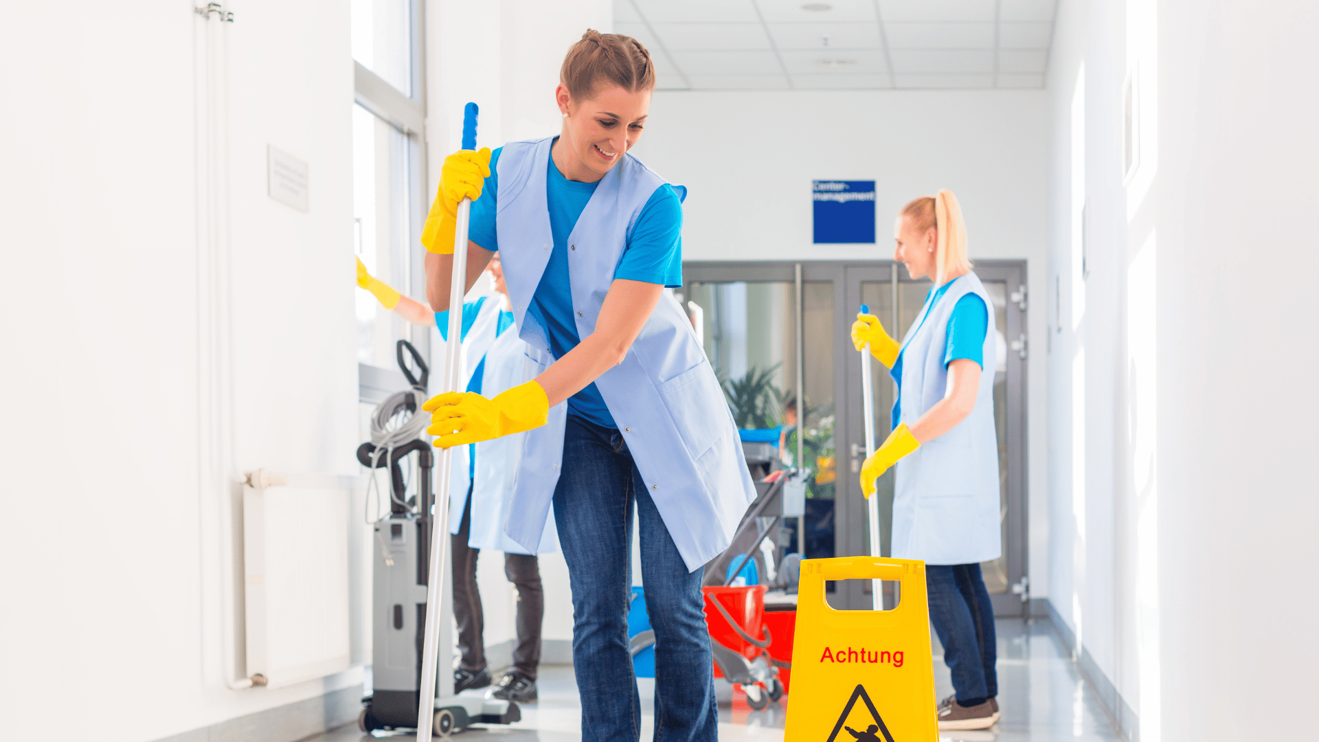 A man and a woman are cleaning the floor in a hallway.