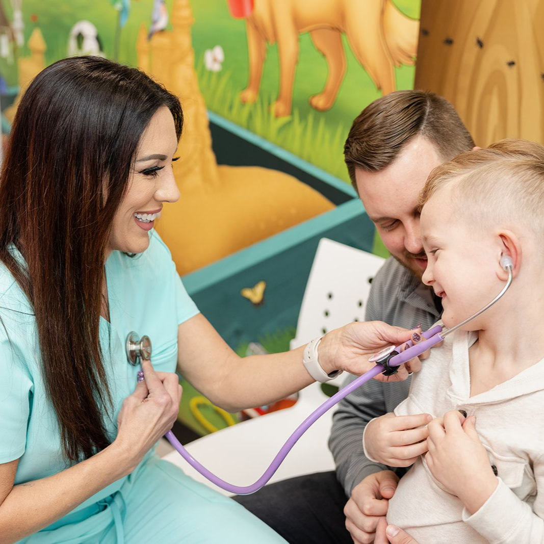 A smiling baby and person lying on a bed. The person looks at the baby with a smile.