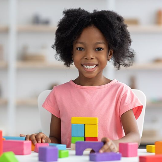 Girl smiling while playing with colorful building blocks.