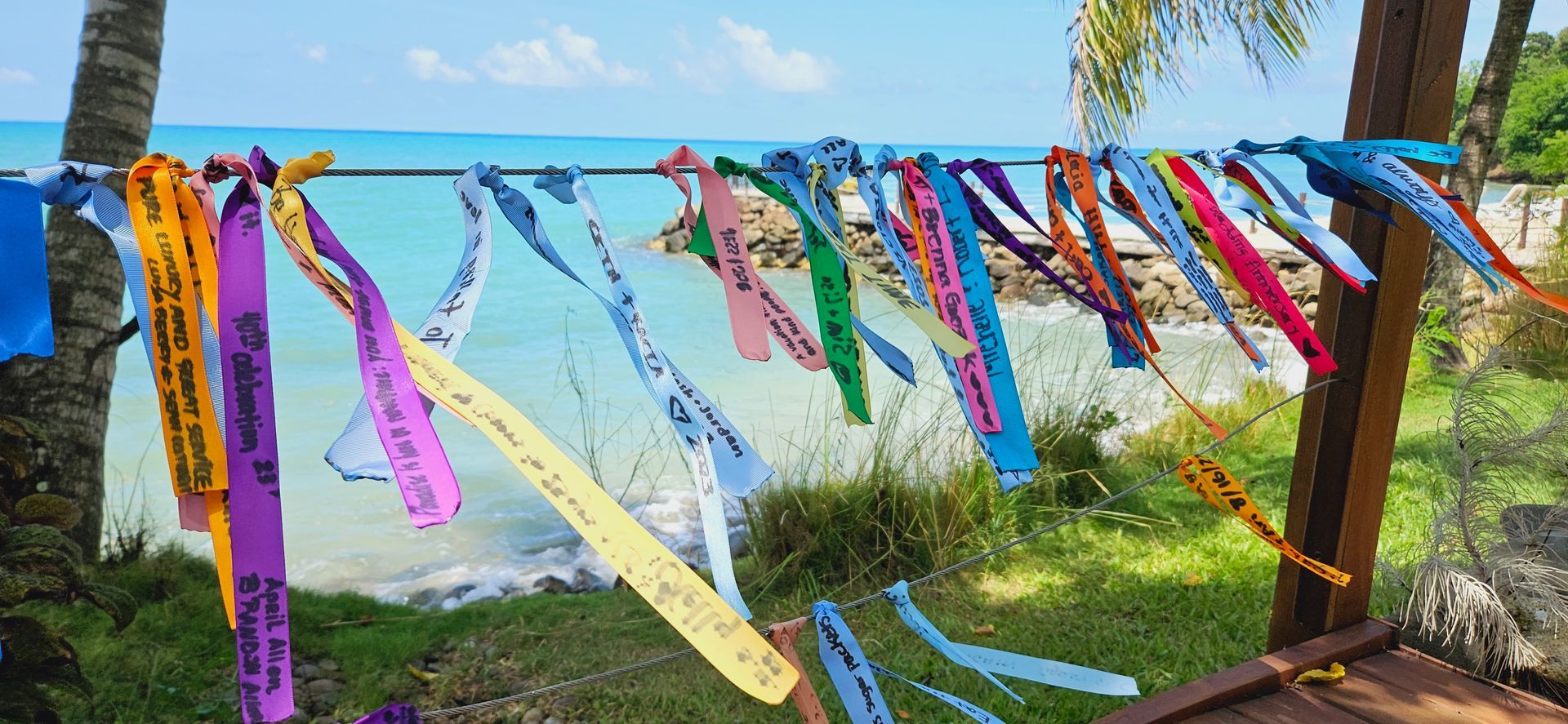 a bunch of colorful ribbons are hanging on a clothes line near the ocean .
