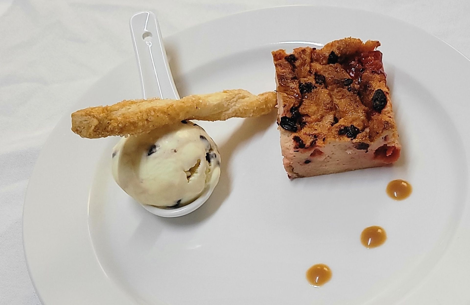 A Christmas dessert sitting on a white plate garnished with ice cream