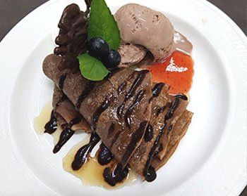 Photograph of Chocolate Crepes garnished with Chocolate Ice Cream and Mint Leaves