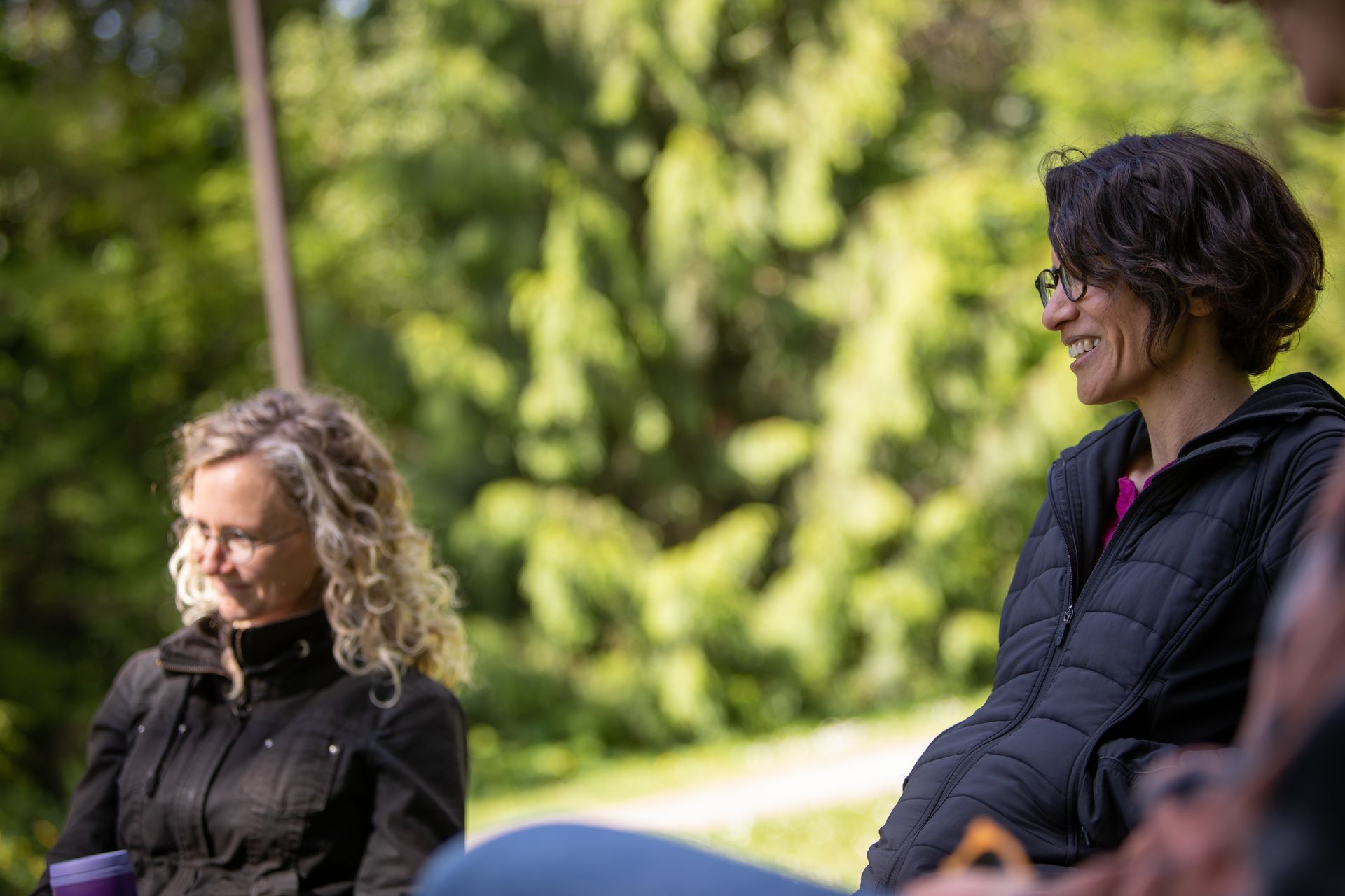 A group of people are sitting in a circle in a park.