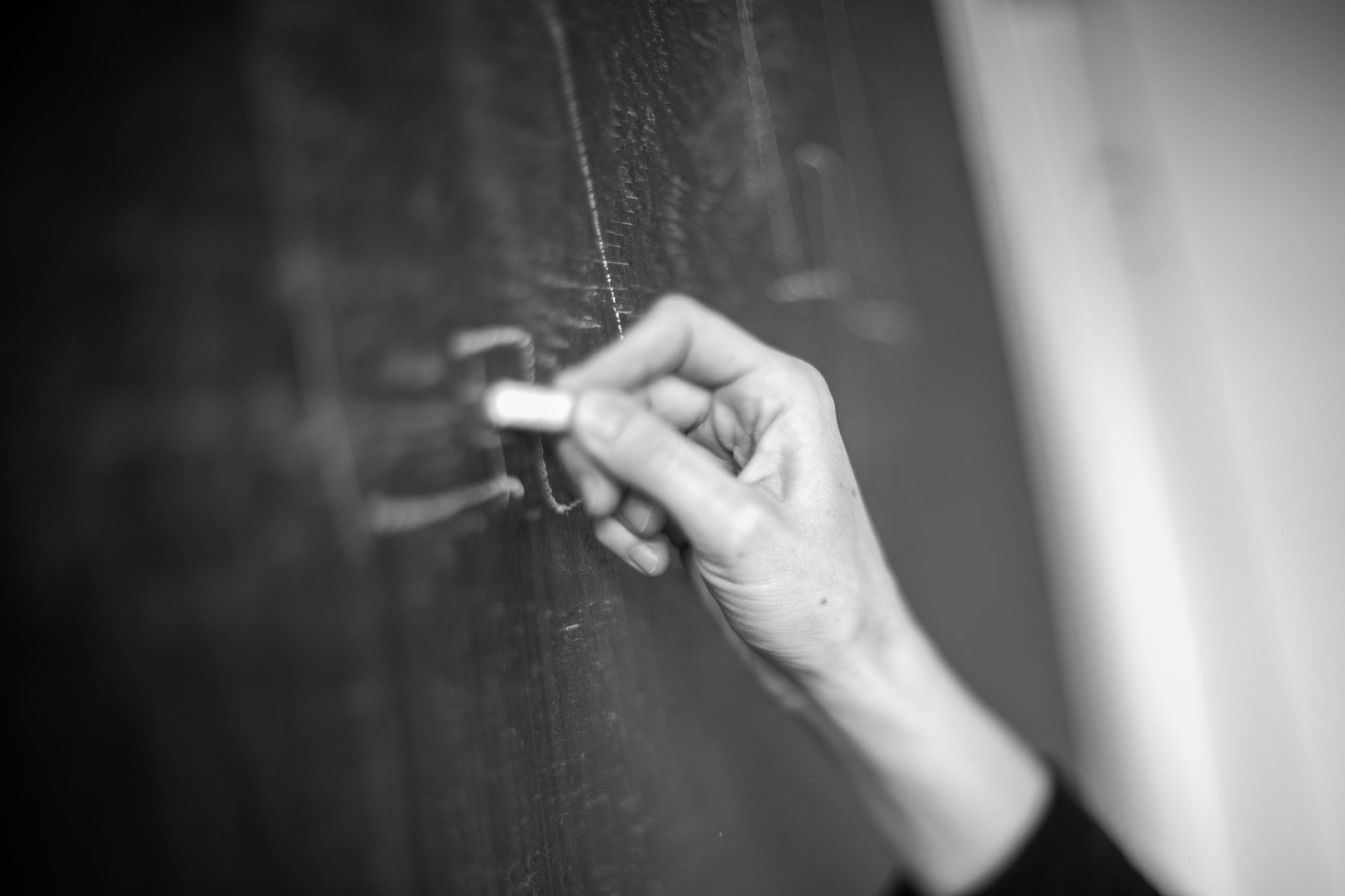 A person is writing on a blackboard with chalk.