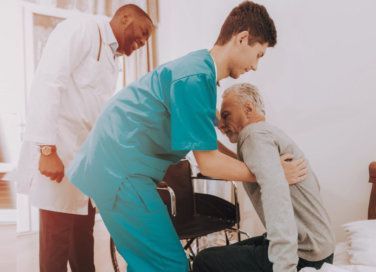 medical assistant helping patient stand up