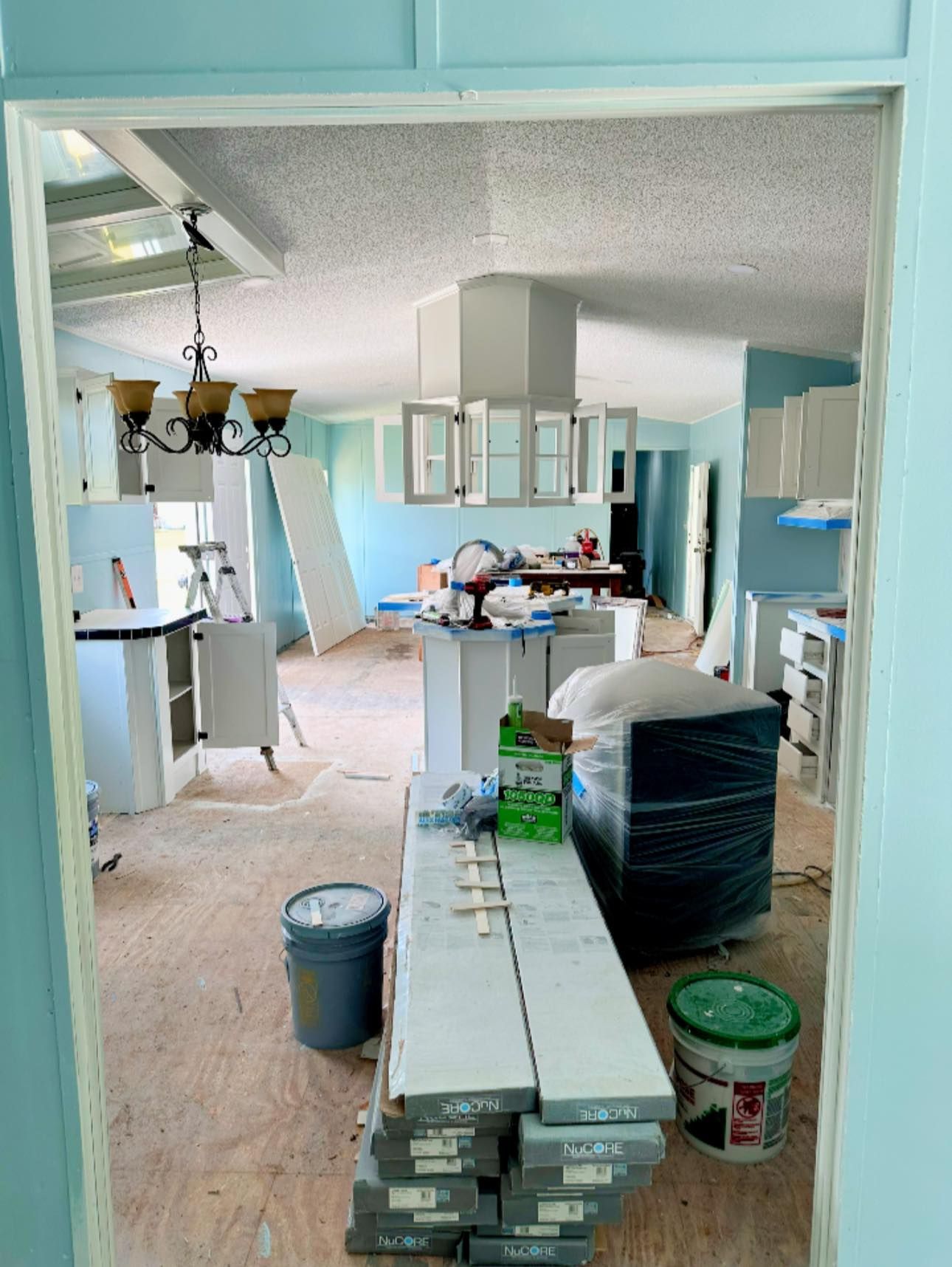 Interior renovation of a kitchen, with new cabinets, exposed flooring, and paint.