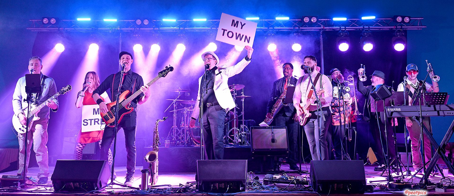 A group of people are standing on a stage playing instruments at a Dead Bettys show.