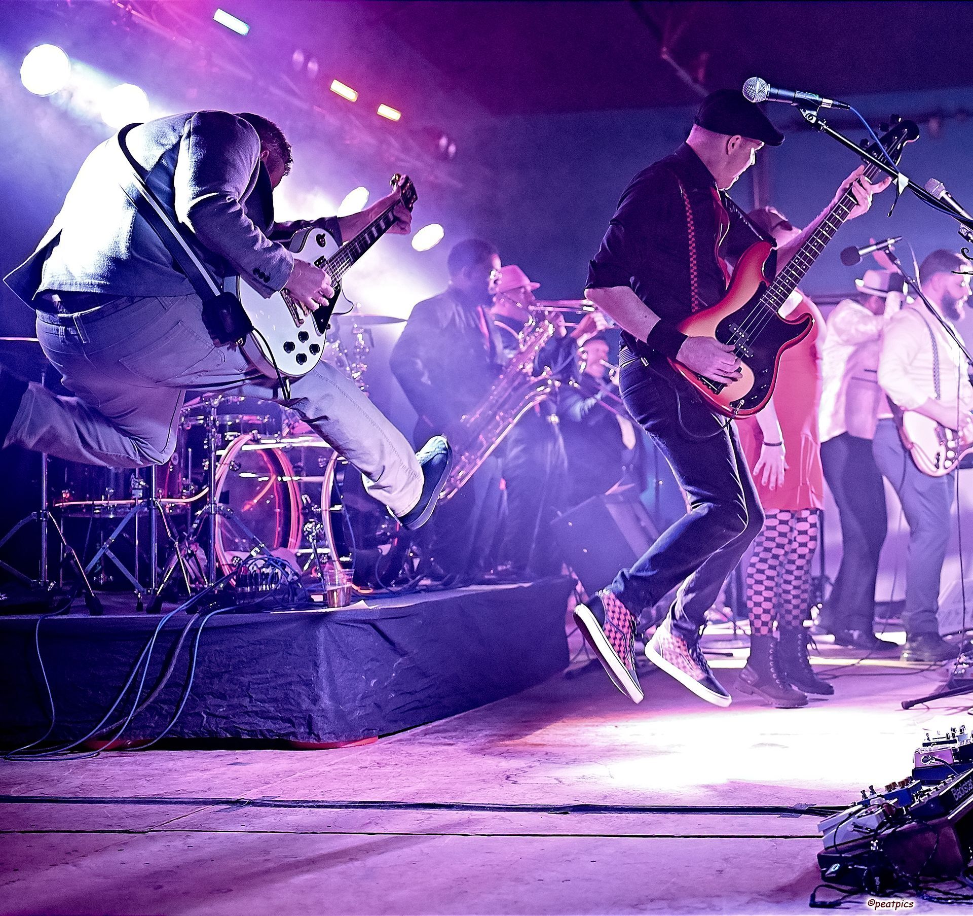A man is jumping in the air while playing a guitar at a Dead Bettys show.