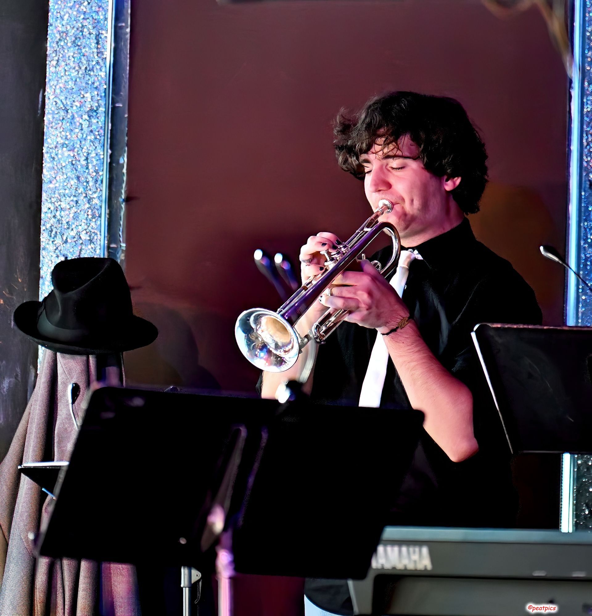 A man is playing a trumpet in front of a yamaha keyboard