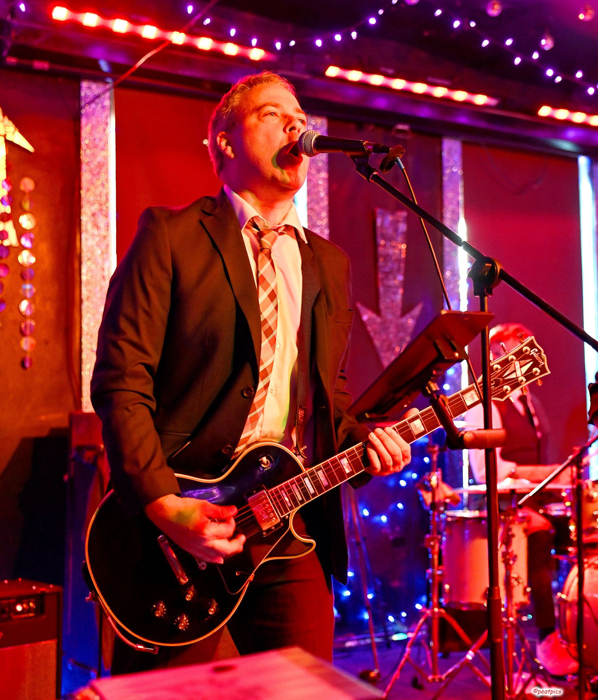 A man singing into a microphone while playing a guitar