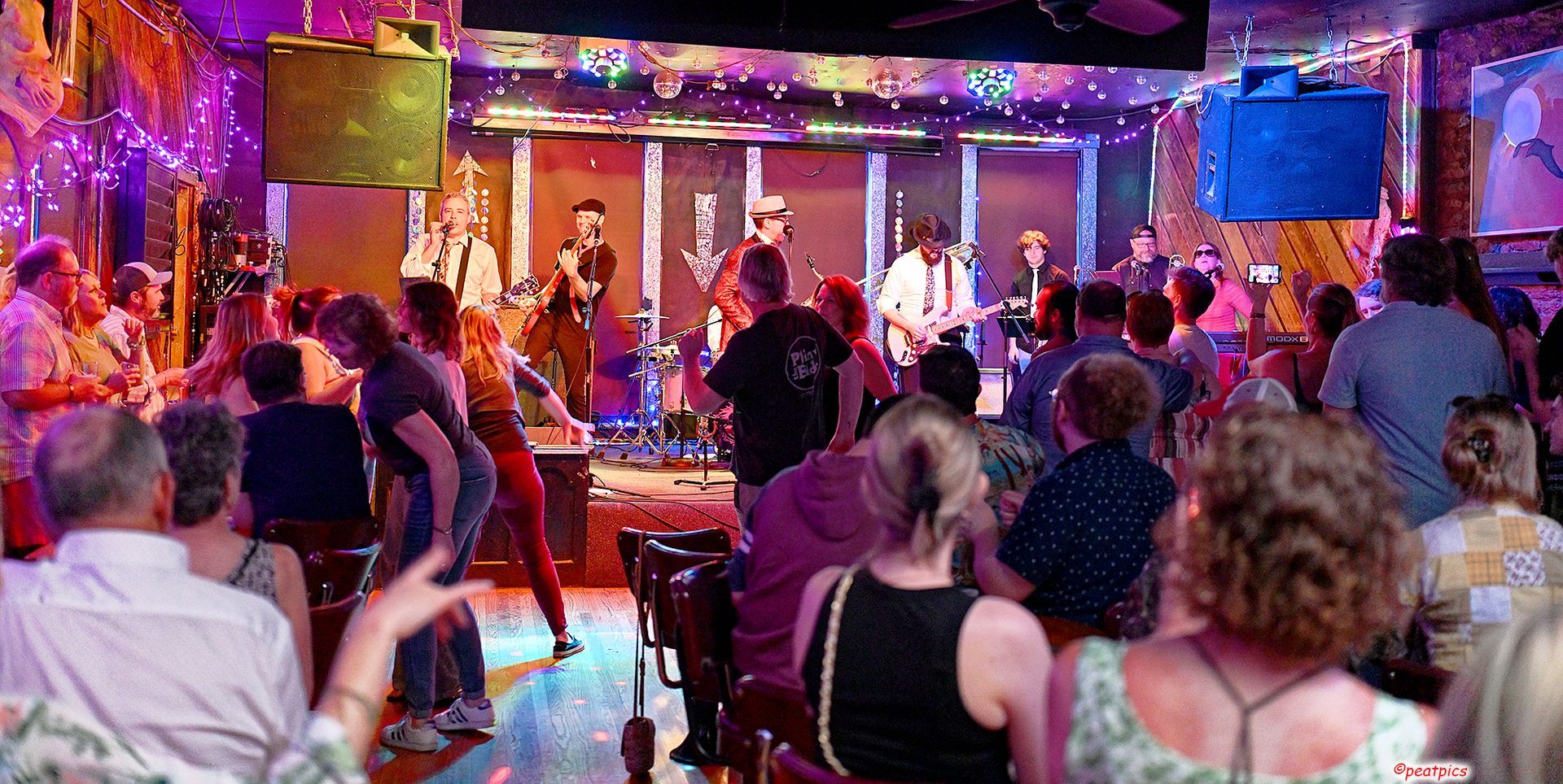 A crowd of people are sitting in front of a stage at a concert.