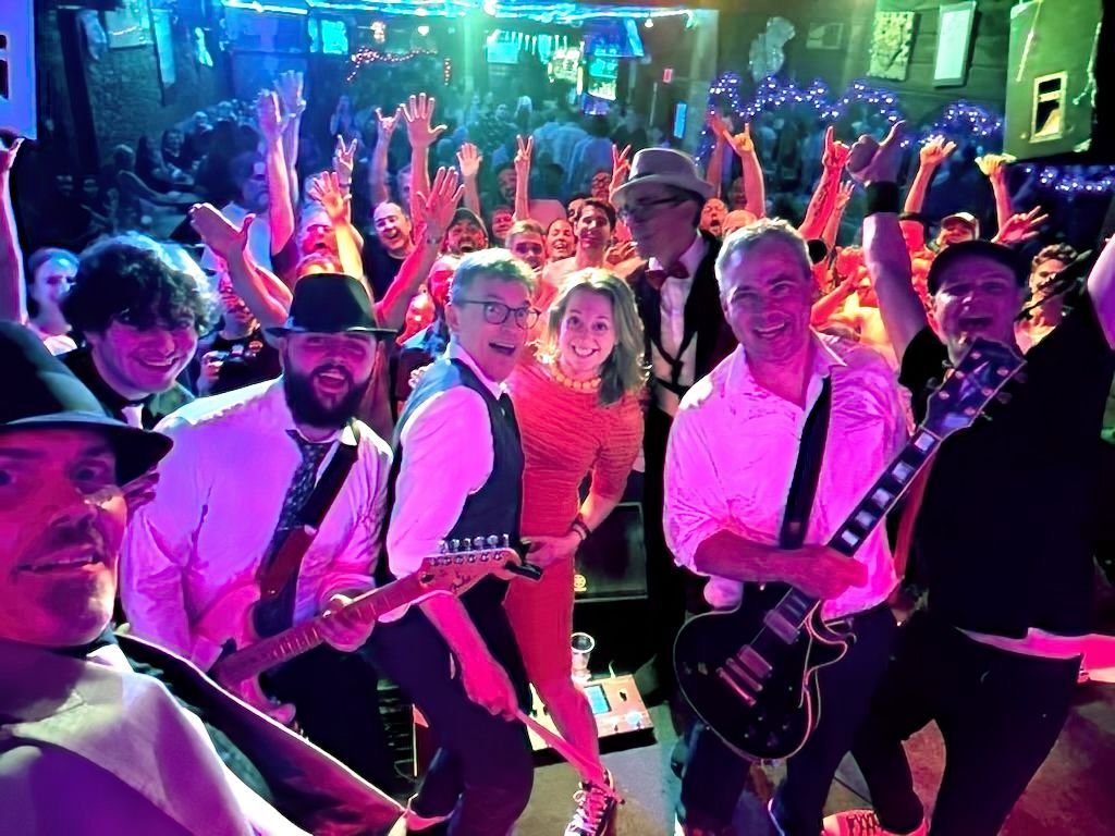 A group of people standing next to each other on a stage with their hands in the air.