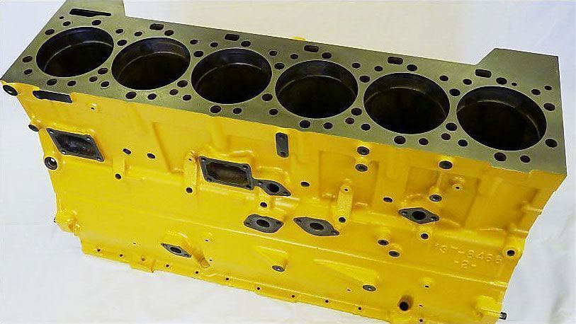 a yellow engine block is sitting on a white surface .