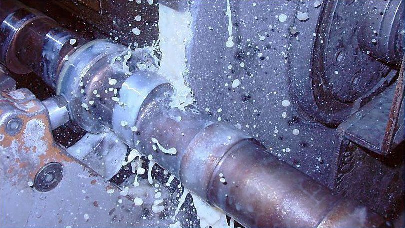 a machine is cutting a pipe with liquid coming out of it .