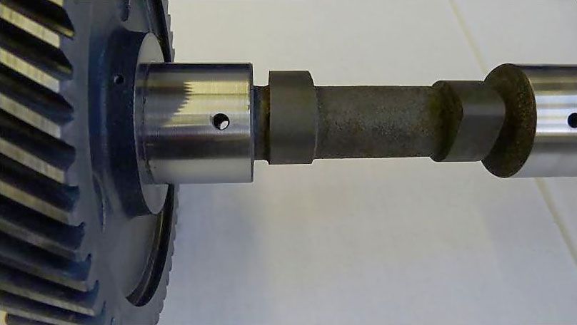 a close up of a gear and a camshaft on a white surface .