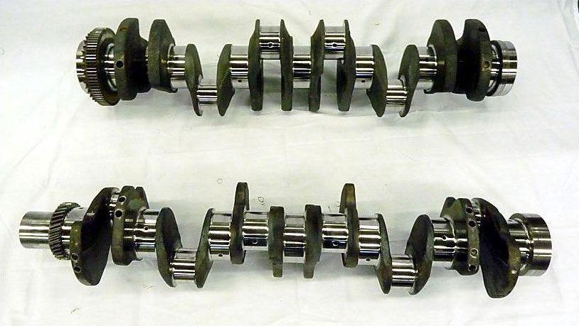 two crankshafts are lined up on a white surface
