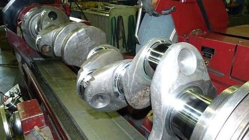 a crankshaft is being grinded on a machine in a factory