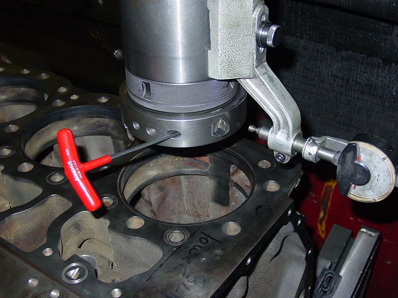 a machine is cutting a hole in a cylinder head