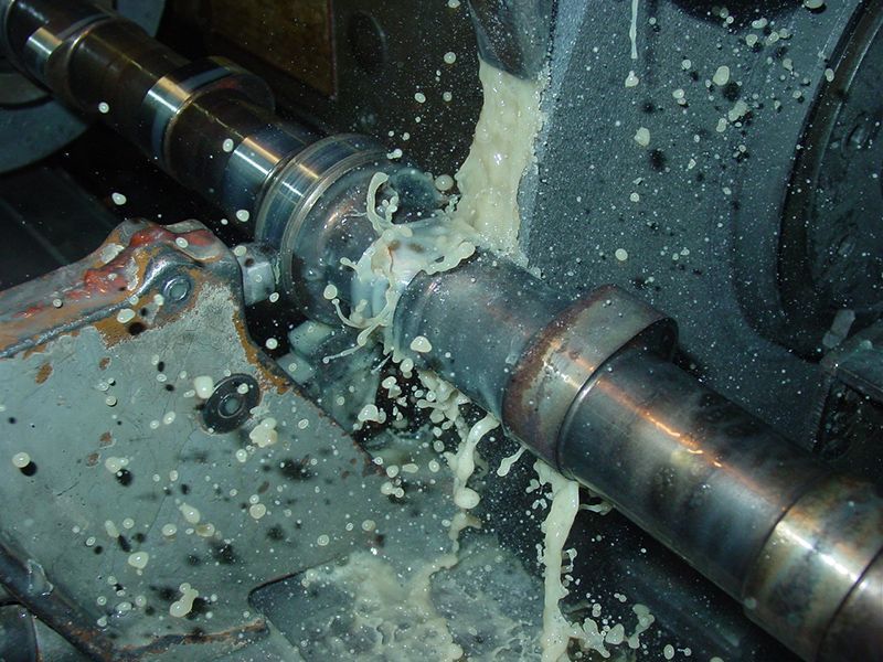 a machine is cutting a piece of metal with liquid coming out of it .
