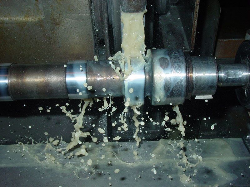 a machine is cutting a piece of metal with liquid coming out of it
