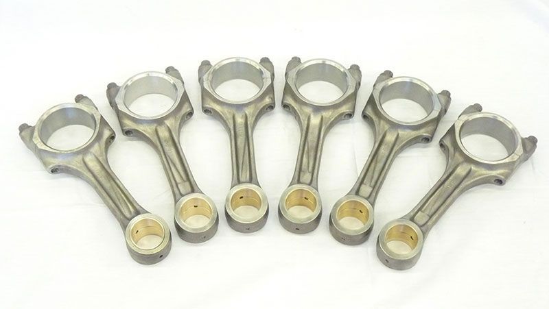 a group of connecting rods are lined up in a row on a white surface .