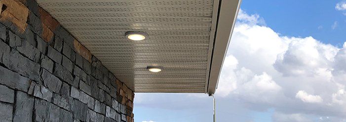 The ceiling of a building with lights on it and a blue sky in the background.