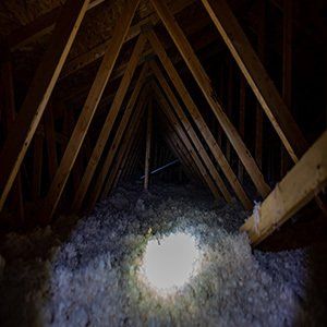 A light is shining through a hole in the attic of a house.