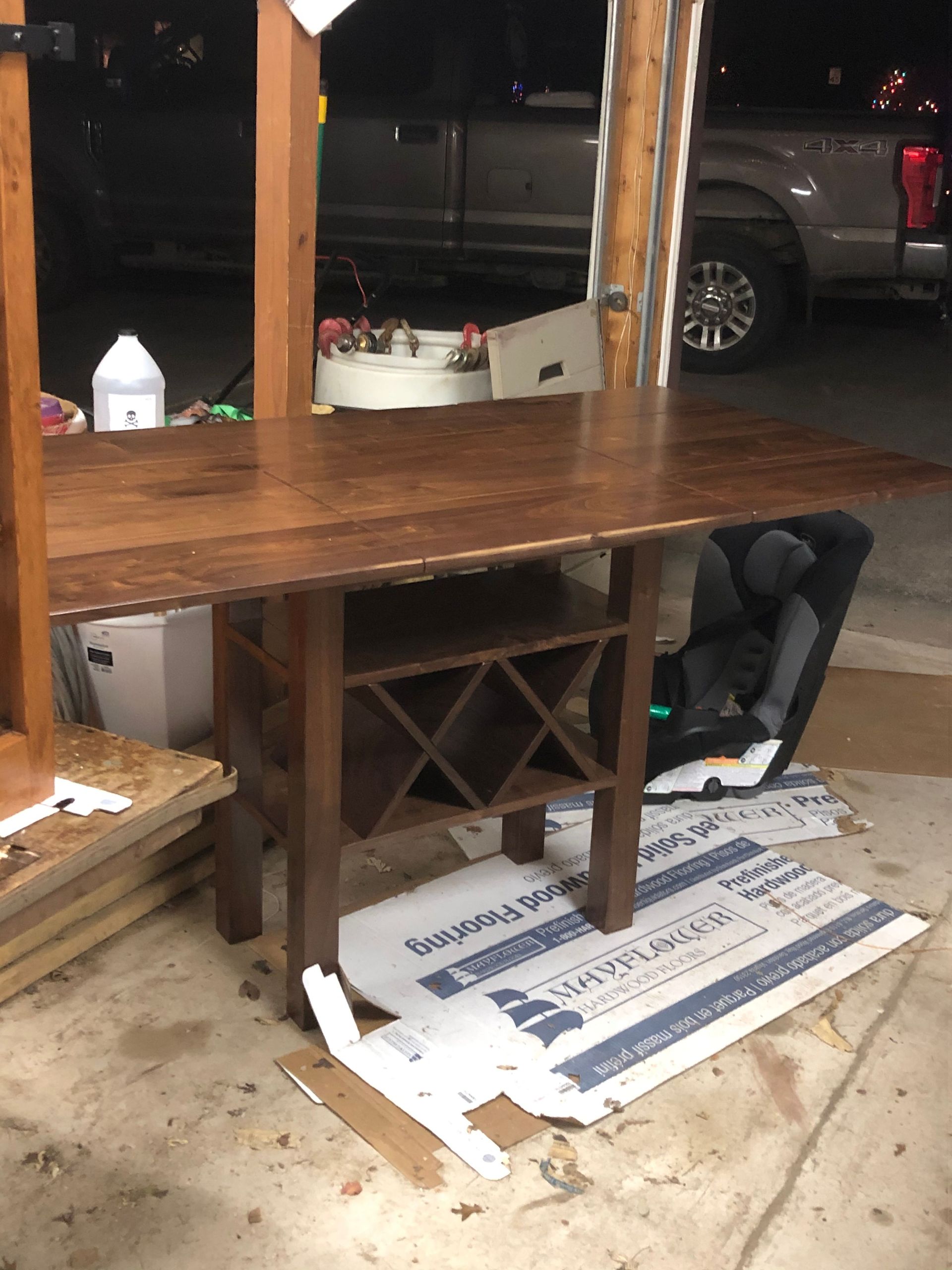 A wooden table is sitting in a garage next to a truck.