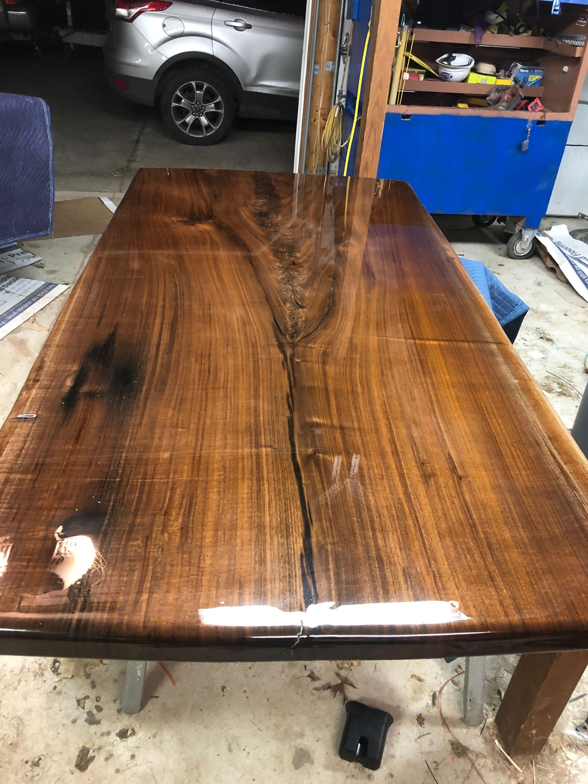 A wooden table is sitting in a garage next to a car.
