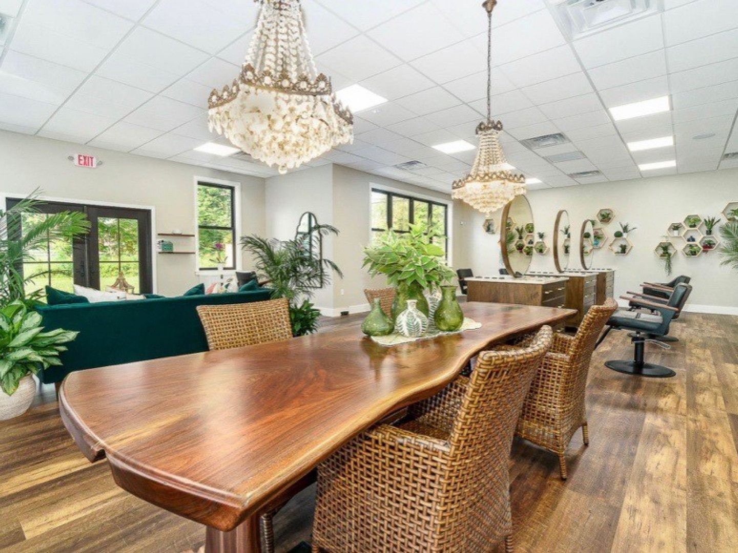 A dining room with a long wooden table and wicker chairs.