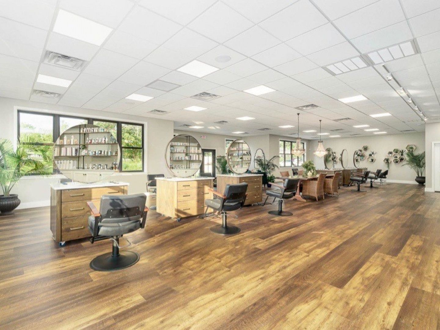 An artist 's impression of a hair salon with wooden floors and chairs.
