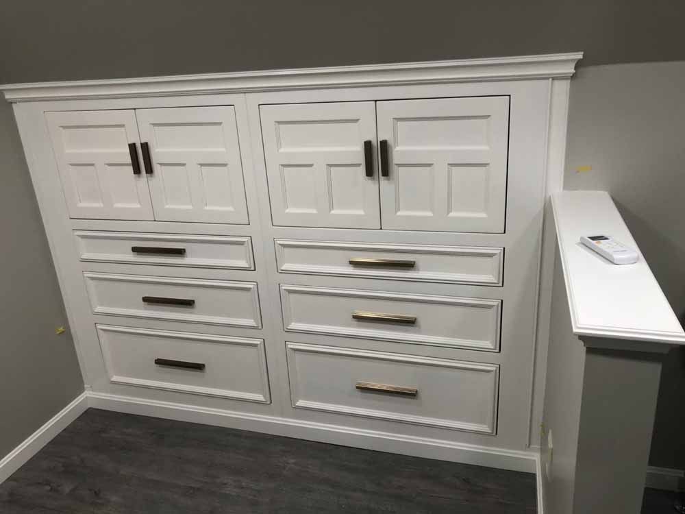A white cabinet with drawers and doors in a room.