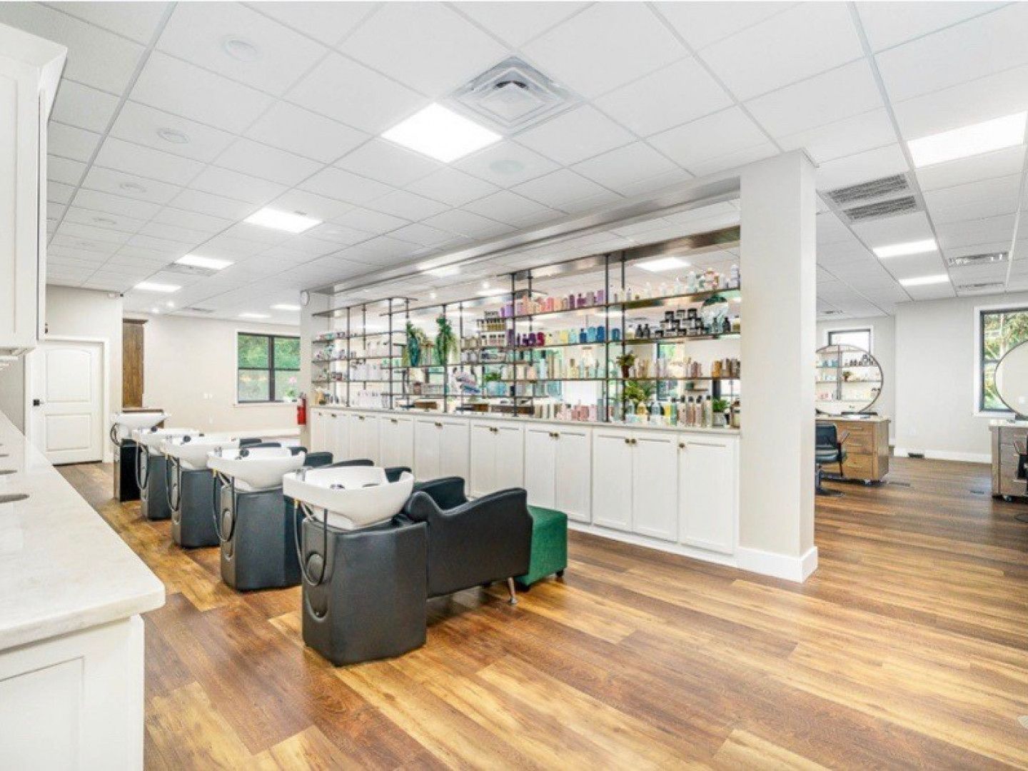 A large room with a lot of chairs and sinks in a salon.
